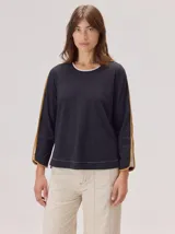 Remera de manga larga color negro con cuello redondo y detalles en contraste color mostaza a lo largo de las mangas. Confeccionada en algodón con elastano y detalles en lino.