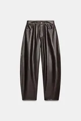 Pantalón de tiro medio con diseño tipo ballon, confeccionado en material con efecto piel. Cuenta con cinco bolsillos, cierre frontal con cremallera y botón metálico.