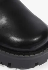 Bota de caña alta color negro, confeccionada en una combinación de cuero liso en la base y material tipo mesh perforado en la caña. Presenta múltiples correas horizontales con hebillas metálicas decorativas y una suela track de goma con taco bajo.