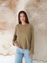 Remera de manga larga color verde oliva, con cuello redondo y tejido acanalado.