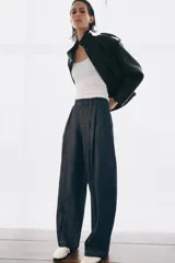 Jeans de tiro alto con corte balloon y largo completo. Presentan cintura con trabillas, bolsillos laterales ocultos, pinzas en el delantero y pespuntes marcados a contraste. Cierre frontal con cremallera, botón y ganchos metálicos.