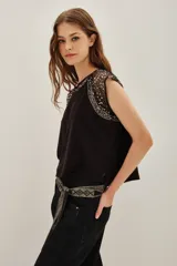 Remera de jersey de algodón grueso color crema, con mangas cortas y cuello redondo. Las mangas y el cuello son de microtul bordado con lentejuelas doradas.