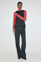 Top negro sin mangas en punto roma, modelo entallado con costuras moldeadoras, cierre oculto en la espalda y diseño de peplum.