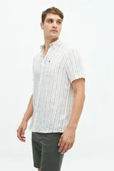 Camisa de manga corta confeccionada en lino y algodón, con fit regular y logo bordado. Color beige con rayas verticales blancas.