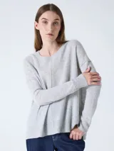 Sweater de cachemira color negro para mujer, con cuello redondo y corte oversized. Presenta costuras externas decorativas, hombros caídos y un diseño ligeramente más largo en la parte trasera con aberturas laterales. Los puños y el bajo cuentan con acabado acanalado.