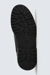 Zapato tipo náutico color negro, con parte superior lisa, bordón y horma redonda. Cuenta con suela de volumen y piso track.