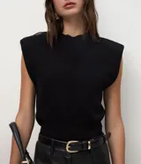 Chaleco de punto negro con cuello redondo, hombreras estructuradas y diseño sin mangas. Confeccionado en tejido de punto con acabado acanalado en el ruedo.