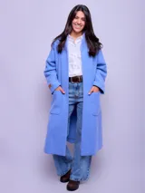 Tapado tipo capa de paño color azul, con cuello mao, bolsillos frontales amplios y diseño abierto sin botones.