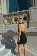 Vestido corto negro con escote halter y cierre frontal con cremallera dorada.