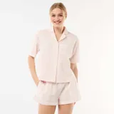 Pijama de dos piezas en color rosado y blanco a rayas finas, compuesto por una camisa de manga corta con cuello solapa, botones frontales y bolsillo en el pecho, y un short a juego con cintura elástica.