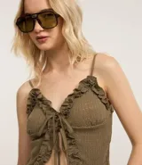 Blusa color verde oliva con breteles finos y escote en V. Presenta volados en el escote y lazo en el centro del busto. El tejido es texturizado.
