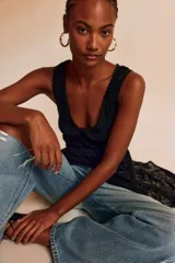 Vestido largo negro de encaje calado, sin mangas, con escote en V, fruncido en el torso y falda larga con transparencias y diseño abierto al frente.