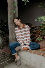 Buzo de algodón y elastano con cuello polo marrón y botones. Diseño de rayas horizontales en blanco, marrón y naranja. Mangas largas con puños naranjas.