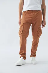 Pantalón cargo color beige, corte slim, con cierre y botón en la cintura, pasacintos, bolsillos cargo con botones y sin puños.