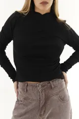 Polera blanca de algodón con cuello alto cruzado y mangas largas.