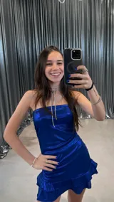 Vestido corto strapless de tejido brillante color azul eléctrico, con frunces y un ruedo con volado.