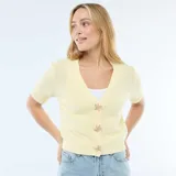 Sweater de punto color amarillo pastel, con cuello en V, manga corta y cierre frontal con botones decorativos en forma de estrella de mar.