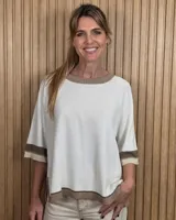 Buzo de punto negro con diseño holgado, mangas codo y detalles en tono tostado y blanco en el cuello redondo, puños y ruedo.