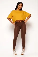 Remera corta de manga corta color celeste, con escote amplio en la espalda que se anuda en la parte inferior, dejando ver un top deportivo amarillo con tiras cruzadas.