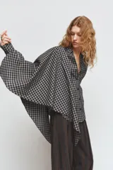 Camisa oversize de algodón con estampado de cuadros, cuello solapa, manga larga con puños y cierre frontal con botones. Presenta un detalle de pañuelo integrado en el mismo tejido que se anuda en la parte frontal.
