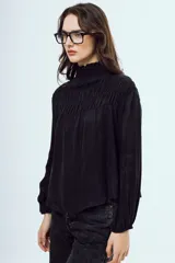 Blusa de seda color negro con cuello alto fruncido y mangas largas abullonadas con puños elásticos.