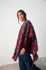 Ruana abierta de tejido de punto con diseño de rayas verticales en tonos fucsia, verde azulado y azul. Presenta terminaciones con flecos en el ruedo y una etiqueta de cuero sintético en el frente.