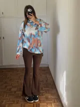 Conjunto compuesto por un sweater de cuello alto con estampado tie-dye en tonos azul, blanco y marrón, y un pantalón de corte acampanado en color marrón con textura acanalada.