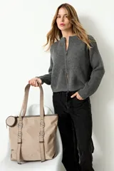 Bolso tipo shopper color beige, confeccionado en poliéster. Presenta doble asa de hombro, cierre principal y detalles de argollas metálicas en el frente. Incluye un pequeño monedero circular removible sujeto a uno de los laterales.