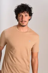 Remera de manga corta con cuello redondo, confeccionada en algodón de color beige. Presenta un pequeño logo bordado de un pingüino en el pecho.