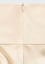 Camisa satinada de color blanco marfil, con diseño recto, cuello alto y manga larga.