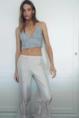 Top crop de satén jacquard color verde agua, con escote en pico adornado con encaje a tono y tirantes finos ajustables. Presenta cierre posterior con ganchos metálicos.
