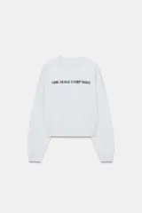 Sudadera gris de cuello redondo y manga larga, con texto "TIME HEALS EVERYTHING" en negro en el delantero. Los acabados son en rib a tono.