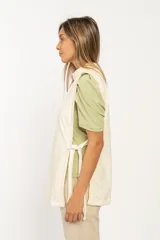 Chaleco color beige de tela tipo gamuza, con cuello alto y lazos en ambos laterales.