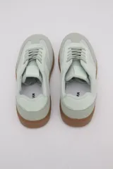 Zapatillas Adidas Samba color verde claro con detalles en blanco y suela de goma color caramelo.