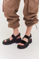 Sandalias de plataforma con suela track, combinando cuero marrón, gamuza y detalles en textura reptil. Cuentan con tira ajustable en el tobillo y diseño ergonómico.