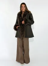 Chaqueta midi color crudo con detalles de piel sintética en el cuello y los puños. Presenta un diseño abierto con bolsillos laterales y una textura suave.