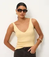 Blusa sin mangas de punto acanalado color crema, con escote en V y espalda descubierta. Confeccionada en una mezcla de viscosa y poliamida, presenta un ajuste al cuerpo y textura vertical en relieve.