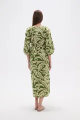 Vestido midi holgado con estampado de hojas en tonos verde y beige, cuello redondo con abertura en V y botones, y mangas 3/4 abullonadas.