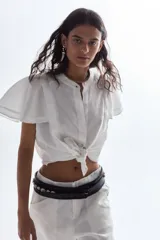 Cinturón negro de cuero vacuno con detalle de caracoles aplicados, hebilla forrada y diseño trenzado.