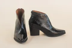 Botinetas negras de cuero charol, con corte en V en el empeine y taco geométrico.