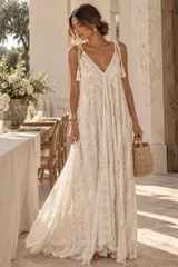 Vestido largo color dorado, confeccionado en tela semitransparente con diseño bordado floral y detalles de brillo. Presenta escote en V, tirantes finos ajustables con borlas en los hombros, y corte amplio y fluido con gran movimiento.