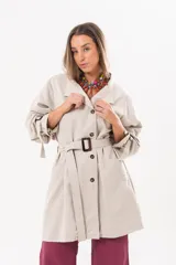 Trench de gabardina Tencel color beige, de silueta relajada, con cierre frontal de botones, lazo desmontable y regulable en la cintura, bolsillos amplios y lazos en los puños.