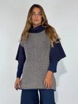 Top de tejido de punto con cuello alto, diseño bicolor con cuerpo estampado en patrón geométrico y mangas cortas tipo capa en color azul liso.