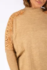 Sweater de punto color beige, con cuello alto y diseño holgado. Presenta detalles de encaje floral en los hombros y mangas, con puños acanalados.