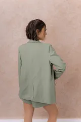 Blazer de lino color verde militar, con solapa clásica, calce recto, cierre frontal de un botón y mangas largas.
