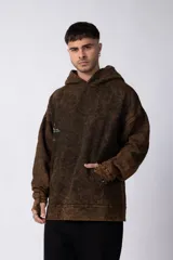 Buzo canguro con capucha, de calce oversize y efecto de lavado ácido en tono marrón. Presenta un bolsillo frontal tipo canguro y un pequeño estampado minimalista en el pecho.