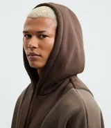 Saco cerrado con capucha, color marrón con recortes contrastantes en un tono más claro de marrón. Confeccionado en algodón y poliéster, tiene cordón para ajustar la capucha, bolsillos tipo canguro y manga larga.