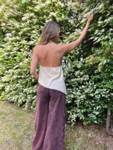 Musculosa color crema de lino y alpaca, con breteles finos que se atan al cuello y detalle de adorno de nácar en el centro del escote.