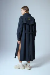 Trench midi color negro, confeccionado en mezcla de algodón y nylon con acabado repelente al agua. Presenta diseño con tajos laterales, bolsillos internos y etiqueta de marca en la espalda.