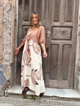 Vestido largo con fondo crudo y estampado de hojas marrones, corte recto con escote en V y breteles anchos.